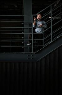 Low angle view of boy standing by railing