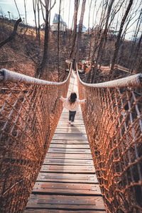 Rear view of woman walking on footbridge