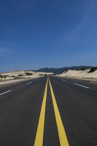 Road passing through landscape against blue sky