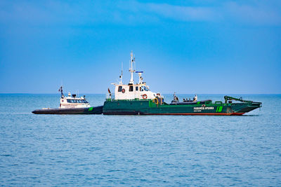 Fishing boat in sea against clear blue sky