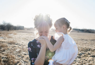 Mother holding her daughter and kissing her hand