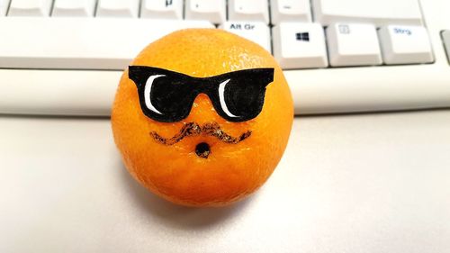 Close-up of anthropomorphic face on orange fruit on table