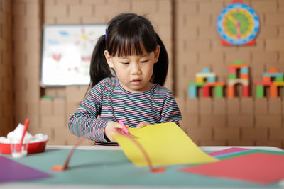 Portrait of cute boy holding paper on table