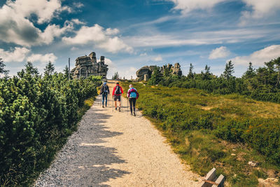 Rear view of people walking on road against sky