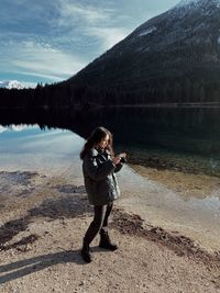 Woman standing at lakeshore against sky