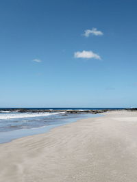 Scenic view of beach against blue sky