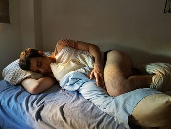 Young man sleeping on bed at home