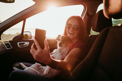 Woman with dog sitting in car