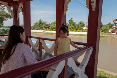 Mother and daughter in gazebo against lake