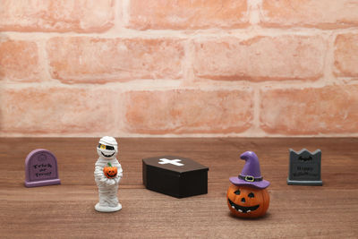 Close-up of toys on table against brick wall