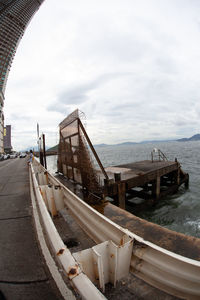 View of abandoned ship in sea against cloudy sky