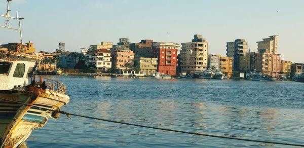 Sea by buildings in city against clear sky