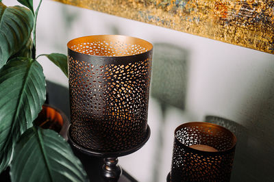 Stylish black room lamp with curly openings for shadows with a home plant with large leaves 
