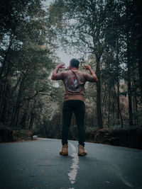 Rear view of man standing on footpath in forest