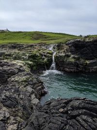 Scenic view of waterfall against sky