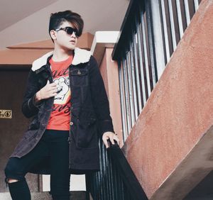Young man standing against built structure
