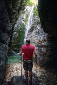 Rear view of man standing by waterfall