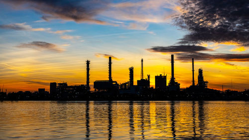 Cranes in city against sky during sunset