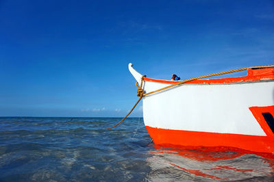 Boat moored on sea against blue sky