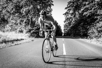 Man riding bicycle on road amidst trees