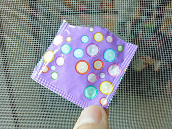 Cropped hand holding condom indoors
