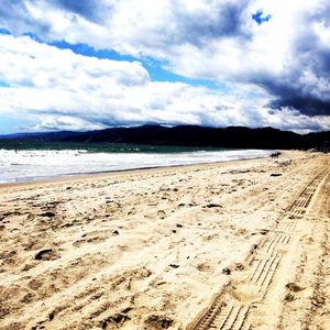 Scenic view of beach against cloudy sky