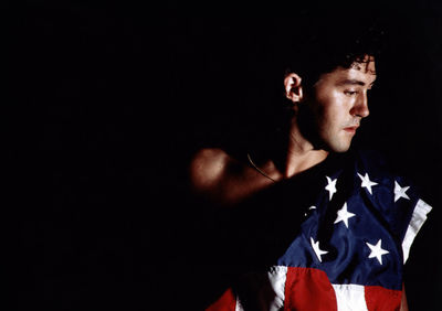 Young man standing against black background