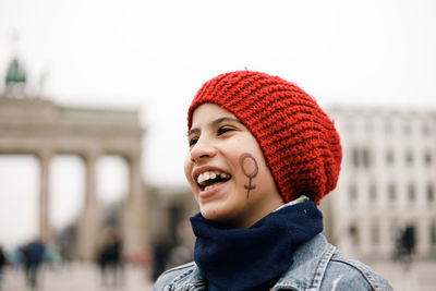 Girl in red cap smiling with face painted with female symbol