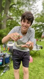 Front view of a young teenage boy holding a snake caught at campsite