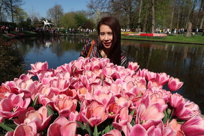 Portrait of woman with pink flowers against lake