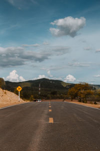 Road leading towards city against sky