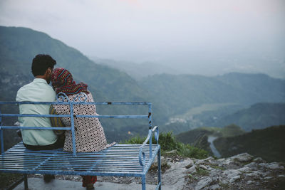 Rear view of people looking at mountains against sky