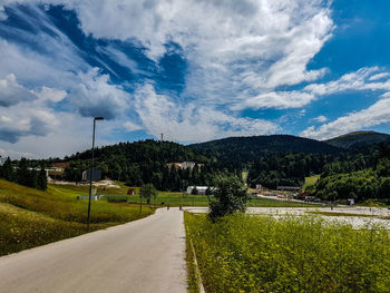 Road amidst green landscape against sky