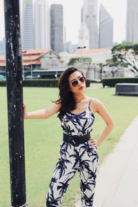 Portrait of young woman wearing sunglasses while standing on footpath