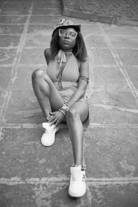 Full length portrait of young woman sitting outdoors