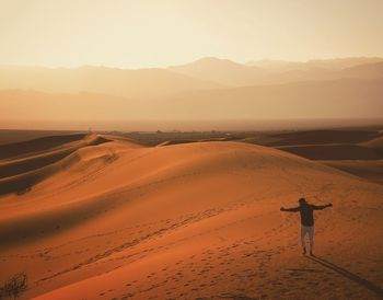 Carefree man with arms outstretched standing at desert