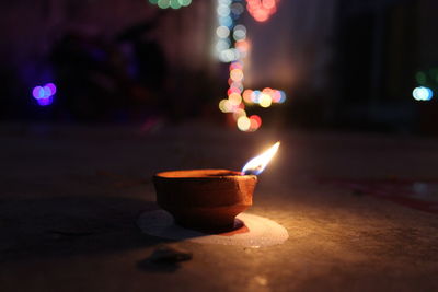 Close-up of lit diya against defocused lights at night