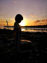 Man looking at sea against sky during sunset