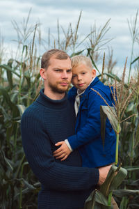 Family walking in corn field at autumn, dad and son posing among high plants