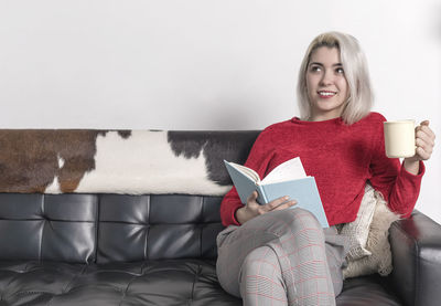 Portrait of young woman sitting on sofa at home