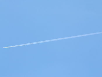 Low angle view of vapor trails against clear blue sky