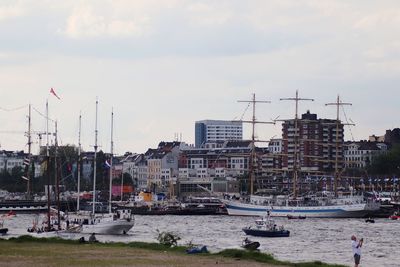 Sailboats moored at harbor against buildings in city