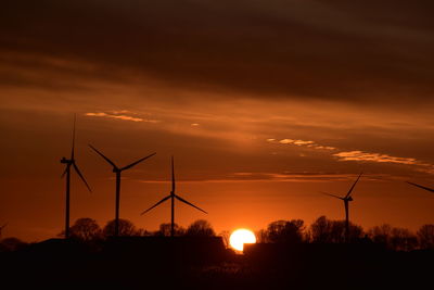 Silhouette windmill on field against sky during sunset