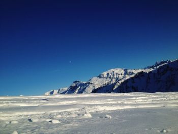 Snow covered mountain against blue sky