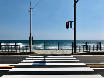 Empty road by sea against sky