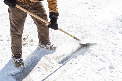 Low section of man shoveling snow on field