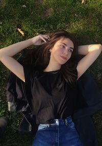 Portrait of young woman sitting on grassy field