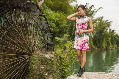 Beautiful woman standing next to water mill in yangshuo