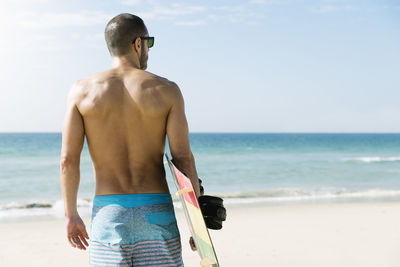 Man with surfboard standing on beach