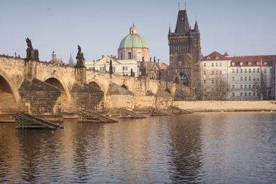 Low angle view of charles bridge and cathedral by river in city against clear sky
